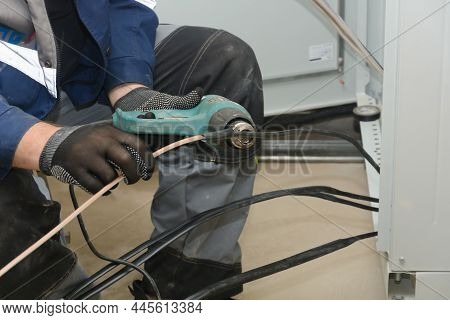 Installation Of The Cable Sleeve Heating Wire Insulation With An Industrial Hair Dryer. Close-up.