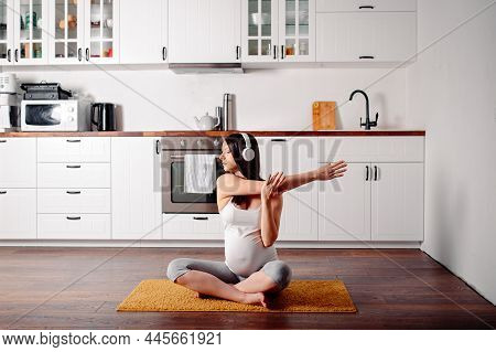 Pregnant Doing Workout On Orange Fitness Mat. Pragnant Yoga At Home In The Kitchen. Pregnant In Whit