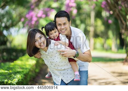 Beautiful Asian Family Portrait Smiling And Happy. Parants Throwing Daugther In The Garden. Happy Fa