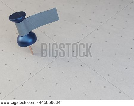 A Blue Thumbtack With A Blank Tape Tag Attached To It On A Textured And Printed Paper Surface -3d Re