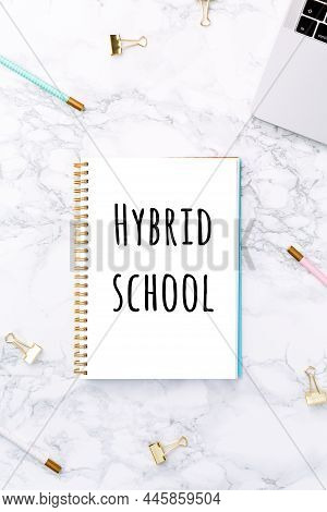 Notepad With Hybrid School Wording, Laptop And Festive Golden Stationary On White Marble Background.