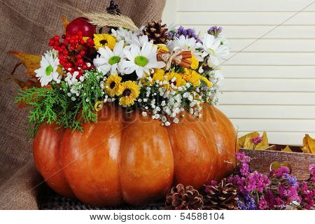 Beautiful autumn composition in pumpkin with bumps and decorative box on table on wooden background