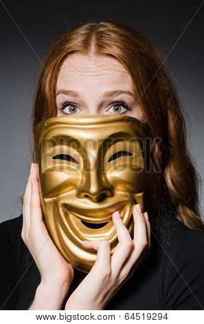 Redhead woman iwith mask in hypocrisy consept against grey background