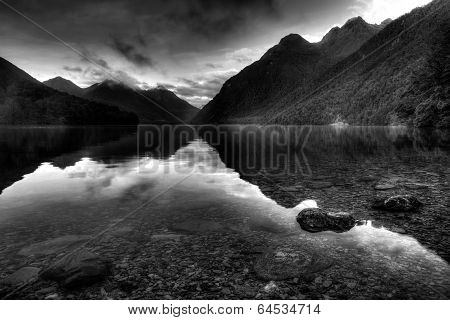 Reflective mountain lake landscape in black and white foreground stones