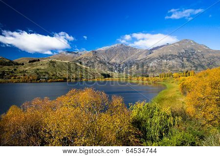 Lake surrounded by Autumn / Fall foliage with Mountain backdrop