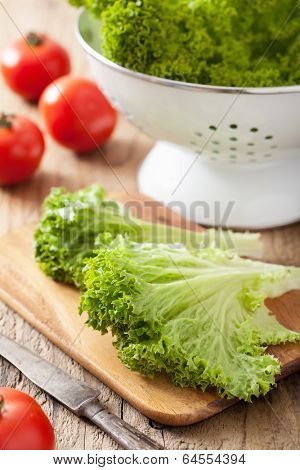 fresh lollo leaves and tomatoes on chopping board for salad