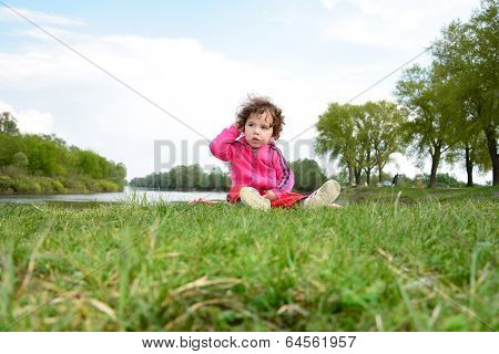 Little Girl Sitting Near The River.