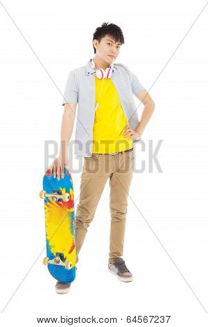 Confident Young Man Standing And Holding A Skateboard