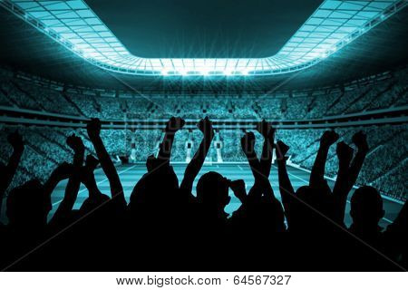 Silhouettes of football supporters against large football stadium with lights