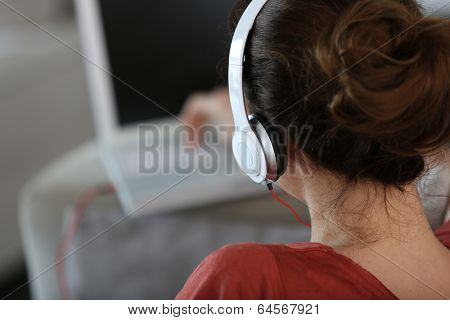 Backview of woman with headphones and laptop