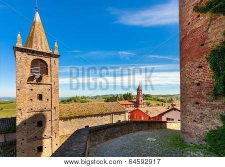 Bell tower and medieval brick wall under blue sky in small town of Serralunga D'Alba in Piedmont, Northern Italy.
