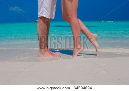 Close up male and female feet on white sand beach