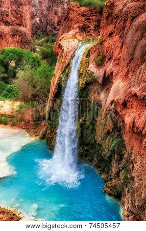 Red rocks of a canyon and falls with blue water.