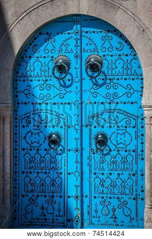 A Blue Door With Black Studs And Stone Ornament At Doorway In Tunisia