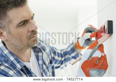 Mid-adult man marking on wall with level