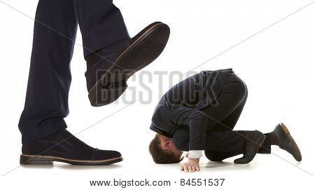 Cared small businessman under big leg his boss, isolated on white background