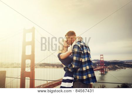romantic couple kissing in front of golden gate bridge with lens flare and retro image filter with warm tones