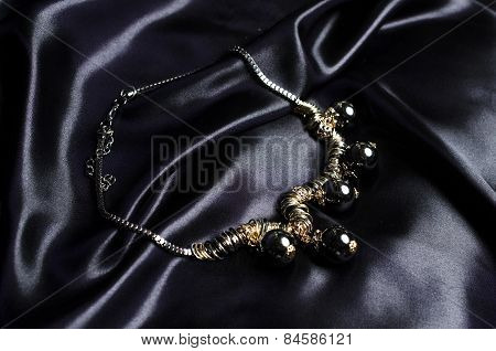 Necklace With Black Beads On Silk Background