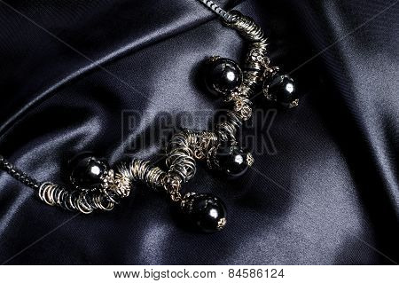 Necklace With Black Beads On Silk Background