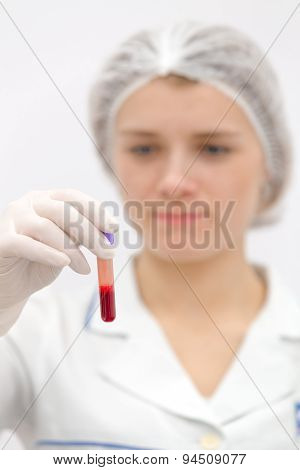Doctor in uniform watching on the test tube with blood