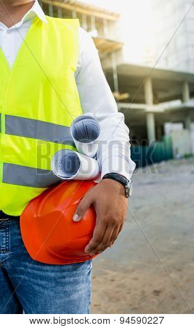 Architect Posing On Building Site With Hardhat And Blueprints