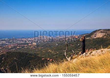 Hiker looking in binoculars enjoying spectacular view on Rosandra valley