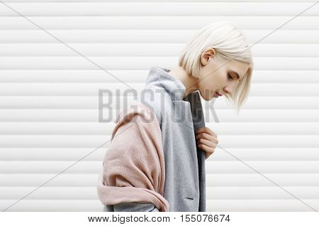 blonde woman on a white background in grey coat