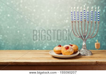 Hanukkah holiday sufganiyot and menorah on wooden table over bokeh background