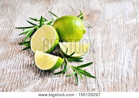 Fresh green lime and rosemary herb on wooden background - 3 selective focus.