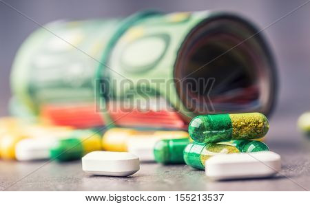 Euro money and medicaments. Euro coins and pills. Rolled euro banknotes stacked on each other in different positions and freely pills around scattered. Toned image.