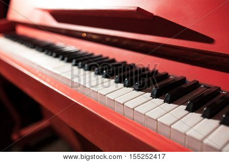 closeup shot of vintage red classical piano; keyboard of antique key music instrument;
