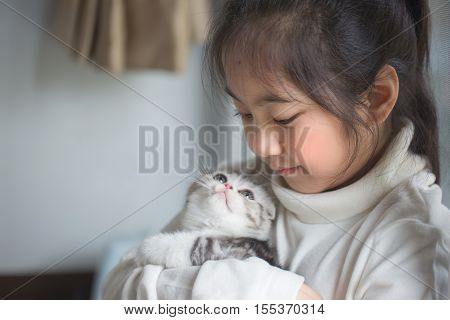 Happy little Asian girl cuddle lovely scottish fold kitten