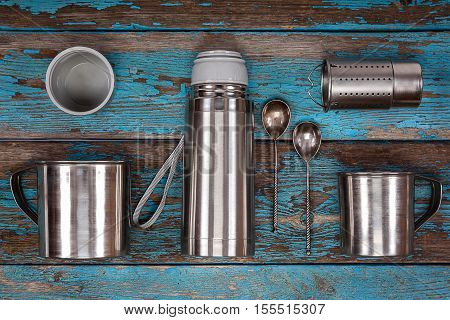 Metal thermos strainer mugs and spoons on a wooden background. Kitchenware. Tea accessories.