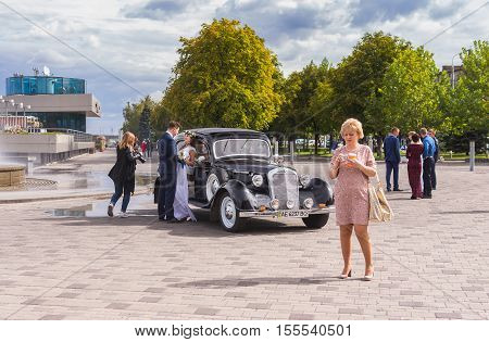 DNEPR UKRAINE - SEPTEMBER 24 2016:Scenery with fiance fiancee vintage car photographer and ordinary people on a Dnepr river embankment in center of Dnepr city at autumnal weekend at September 24,2016