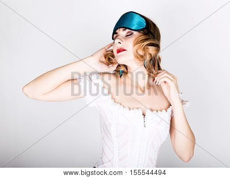 beautiful young woman in a pink dress and points for sleep, standing and posing. sleeping eye covering mask.