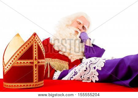 Saint  Nicholaswith mitre on table is tired and asleep. Isolated on white background
