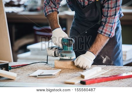 Worker grinds the wood of angular grinding machine.