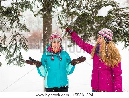 Happy friends having fun in winter cild snowing weather at park.