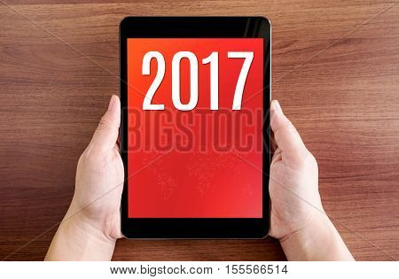 Hand Holdling Tablet With 2017 Year Number On Screen On Wood Table,digital Happy New Year Card, Leav