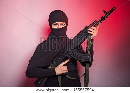 woman with a machine gun. An armed woman shoots. Woman holding an automatic weapon. Concept of war and terrorism.