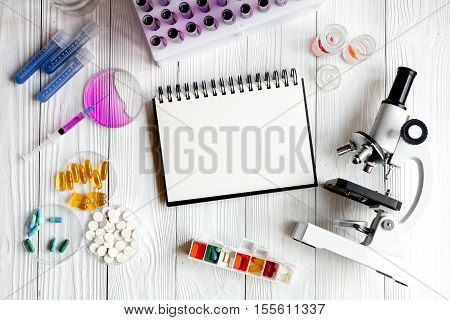medical student working place with blank open notebook and microscope at wooden table top view