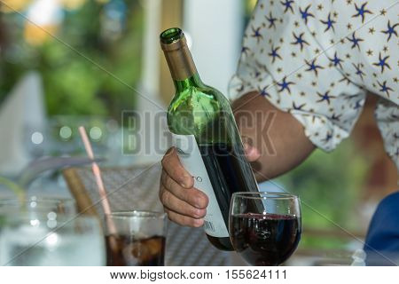 Cayo Guillermo, Iberostar Daiquiri, Cuba, Aug. 20, 2013, amazing fragment of view of a Waiter hand holding and ready to serve a fresh opened red wine bottle at the restaurant