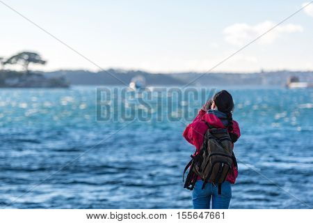 Woman photographer taking pictures of moving boat and harbour. Exploring adventure concept
