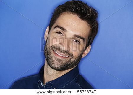 Smiling confident young man in blue studio portrait