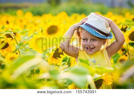 Happy little girl on the field of sunflowers in summer. beautiful little girl in sunflowers