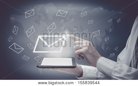The concept of email marketing. Businessman makes sending emails from your tablet.
