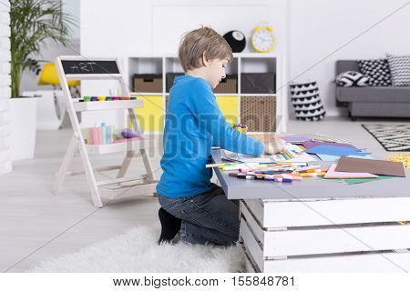 Focused Young Boy Is Sitting At Table