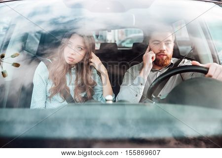Pretty couple in car. man talking at phone. girl offened