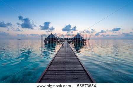 Panorama of tropical island. Turquoise water lagoons coral reefs visible. Sunrise sky and clouds painted in pink. Tourist Resort Deluxe. Maldives