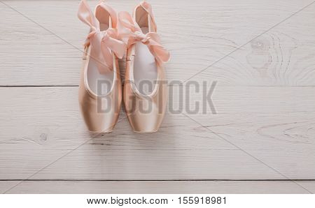 Pastel pink ballet shoes background. New pointe shoes with satin ribbon lay on white rustic shubby chic wood, top view with copy space